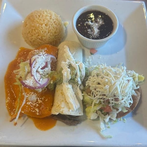 A Mexican combination plate with an enchilada, burrito, tostada, rice, and black beans.