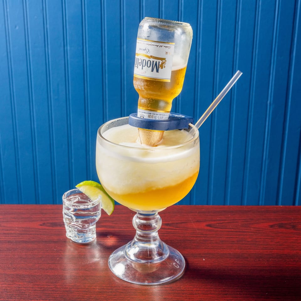 Frozen cocktail topped with an inverted Modelo bottle.