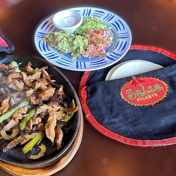 Sizzling fajitas with steak, peppers, and onions, served with guacamole, pico de gallo, and tortillas.