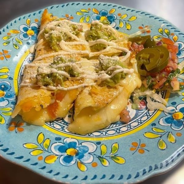 Cheesy enchiladas topped with guacamole, sour cream, and cotija cheese, served with pico de gallo.