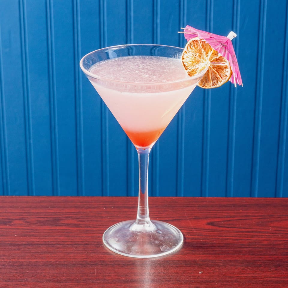 Pink Cosmopolitan cocktail with citrus garnish.