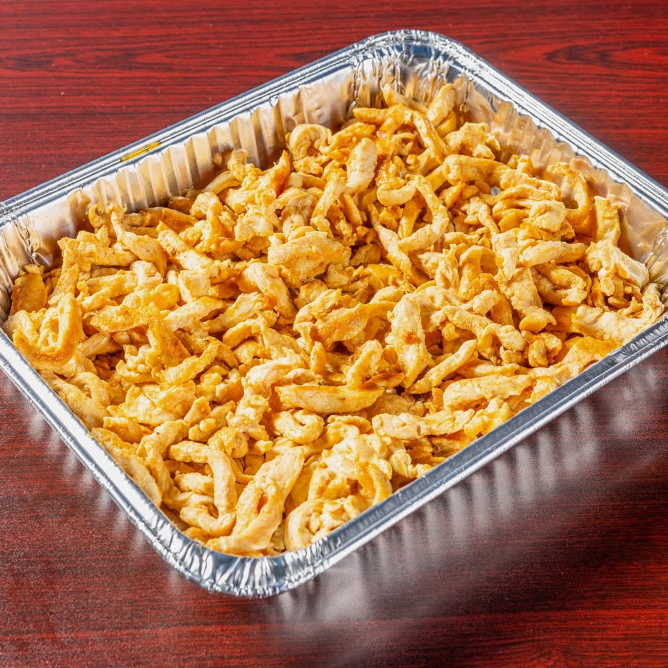 Catering tray of sliced chicken, viewed at an angle.