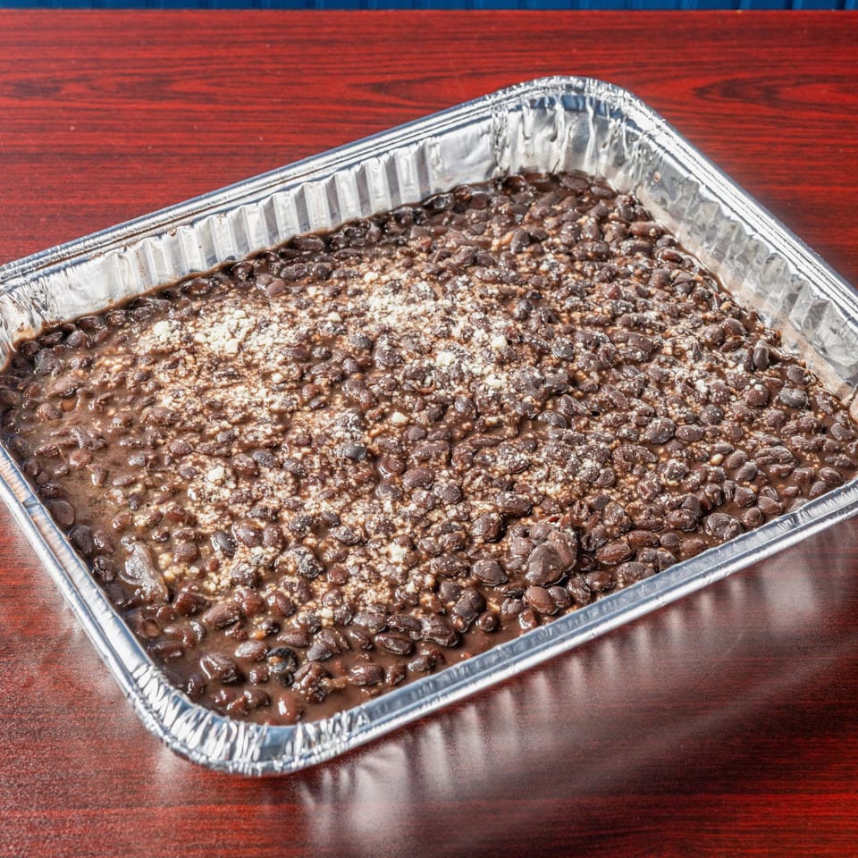 Tray of black beans topped with cheese.